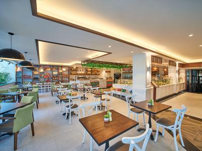 Helles, modernes Restaurant mit weißen Stühlen, Holztischen und großer Fensterfront.