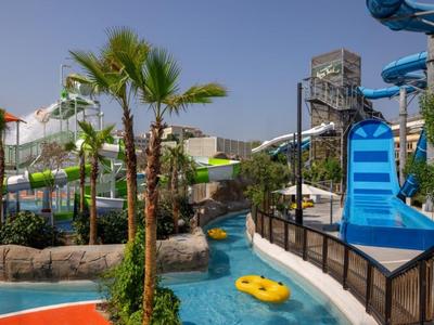 Vodní park se skluzavkami, palmami a línou řekou pod jasnou oblohou