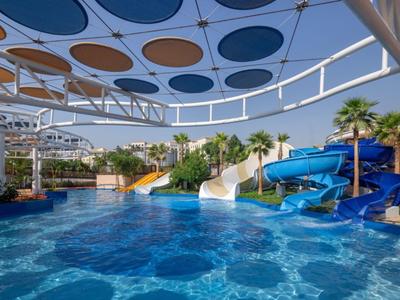 Bunter Wasserpark mit Wasserrutschen, Pool und Sonnenschutz mit runden Elementen.