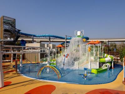 Vodní park s tobogány, vodní mlhou a barevnými herními prvky pod čistou oblohou.