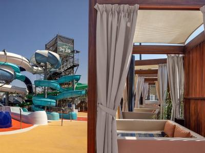 Vodní skluzavky a soukromé zastřešené lehátka v slunečném vodním parku.