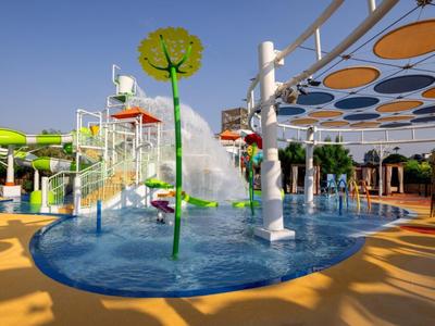 Vodní hřiště s barevnými skluzavkami a stříkajícími fontánami pod jasnou oblohou.
