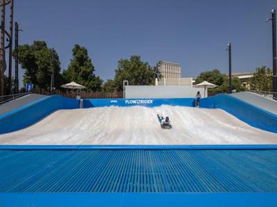 Osoba provozuje flowriding na umělé vlně v aquaparku za slunečného dne