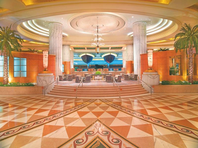 Elegantní hotelová lobby s vysokými sloupy, luxusním interiérem a geometrickou mramorovou podlahou.