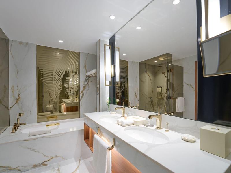 Moderní koupelna s vanou, velkým zrcadlem a stylovými armaturami.