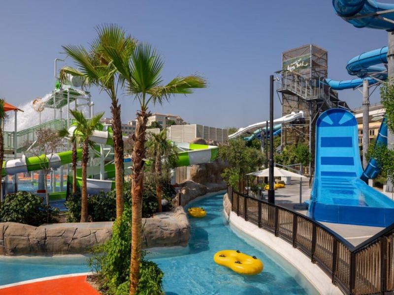 Vodní park se skluzavkami, palmami a línou řekou pod jasnou oblohou