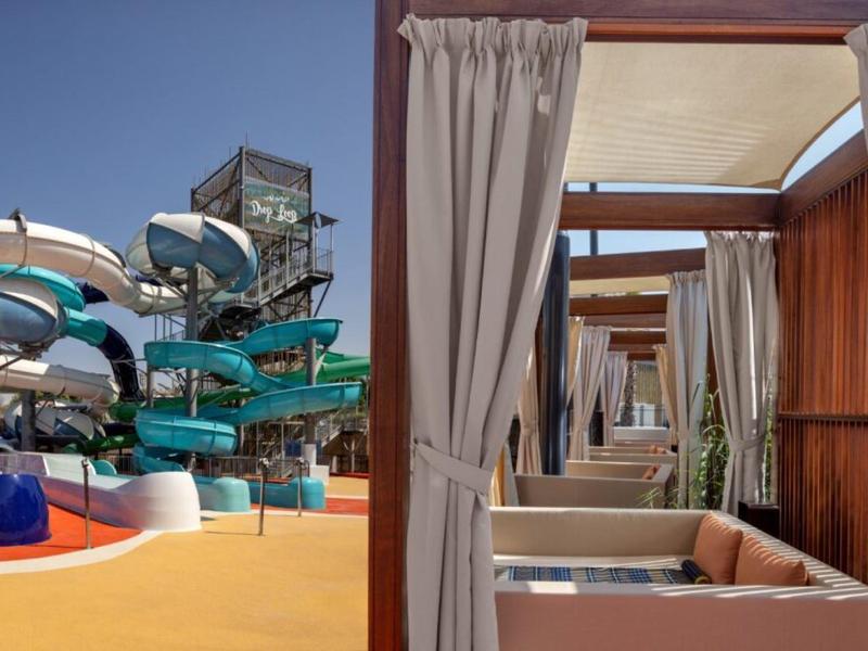 Vodní skluzavky a soukromé zastřešené lehátka v slunečném vodním parku.