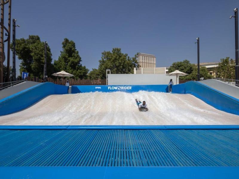Osoba provozuje flowriding na umělé vlně v aquaparku za slunečného dne