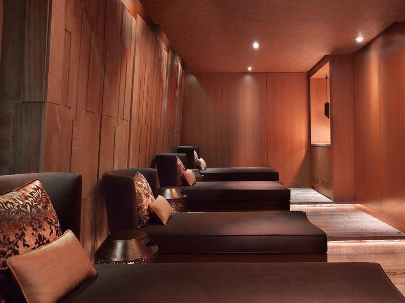 Pohodlná lounge s tmavými pohovkami a teplým dřevěným dekorem v hotelu.