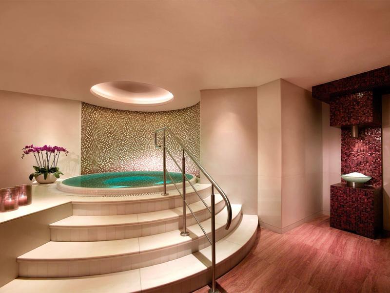 Elegantní wellness prostor s vířivkou, schody a nepřímým osvětlením.