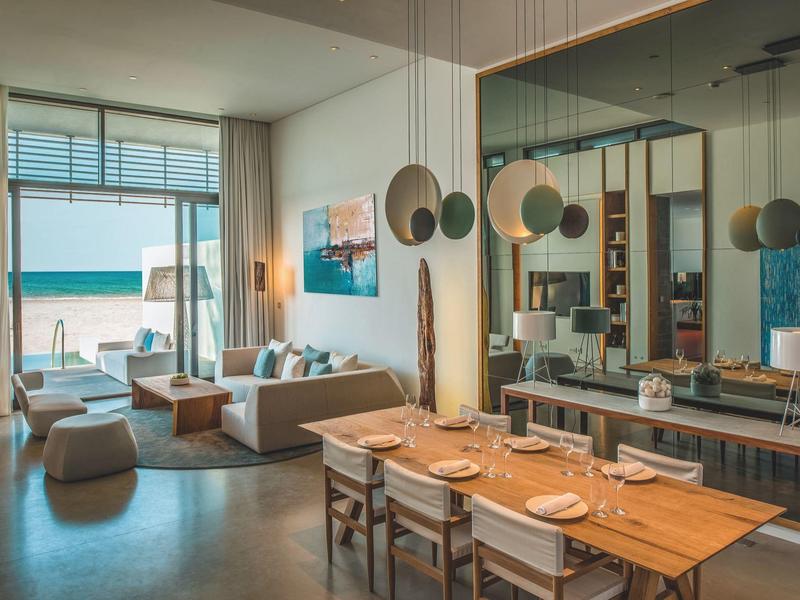 Modern living and dining area with sea view and terrace in a hotel room.