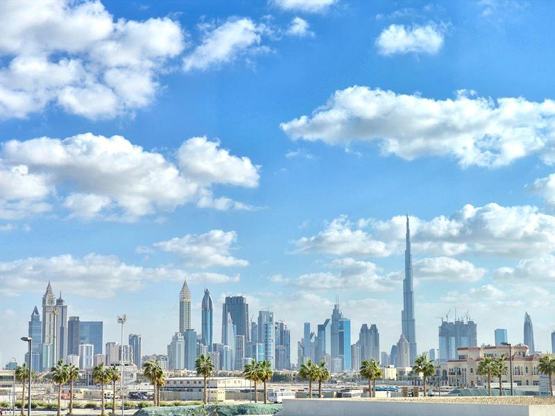 Skyline of a modern city with skyscrapers under clear sky and palm trees in the foreground