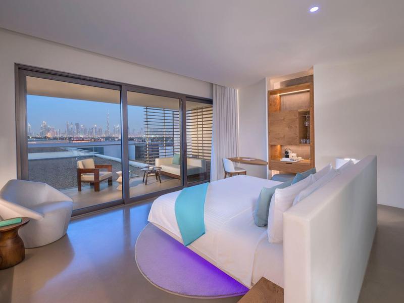 Modern hotel room with large bed and balcony overlooking the city