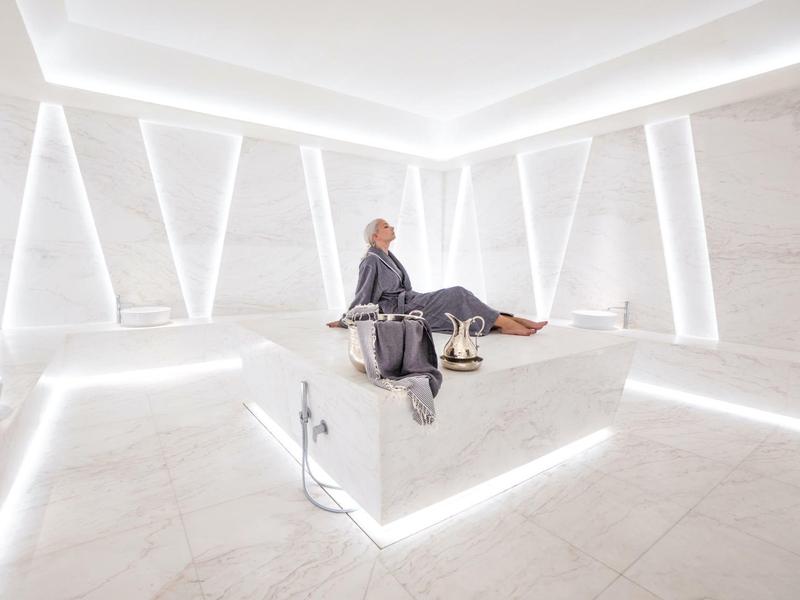 Modern, bright spa sauna area with a man sitting on a lounger.