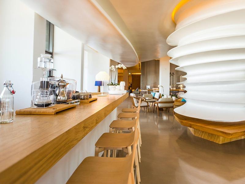 Modern hotel lounge area with wooden counter, bar stools, and stylish lighting.
