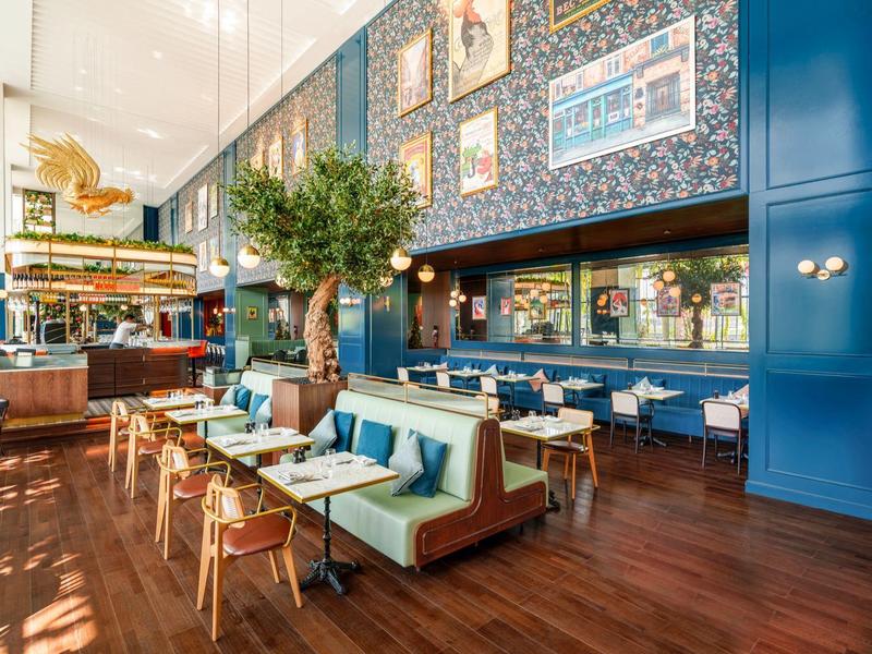 Licht, modern hotelrestaurant met houten vloeren en grote groene zitbanken.