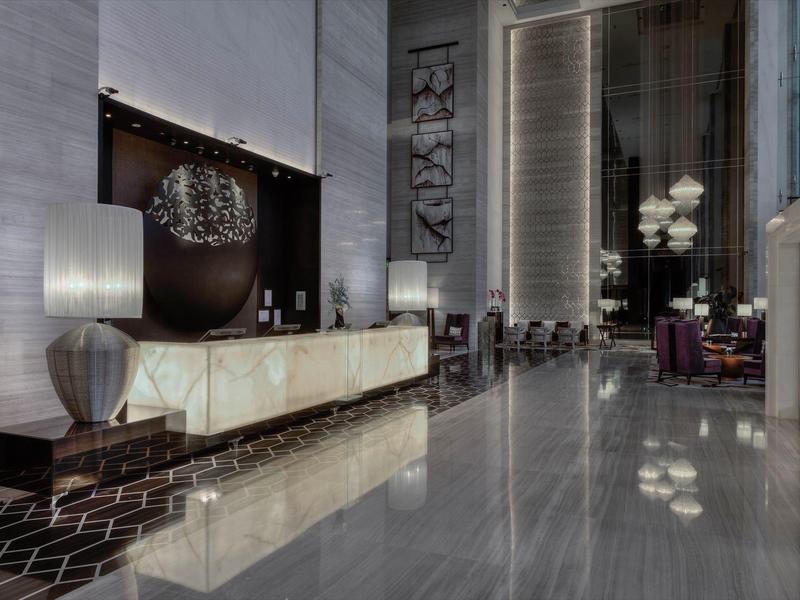 Luxe hotel lobby met marmeren vloeren, moderne sculpturen en elegante verlichting.
