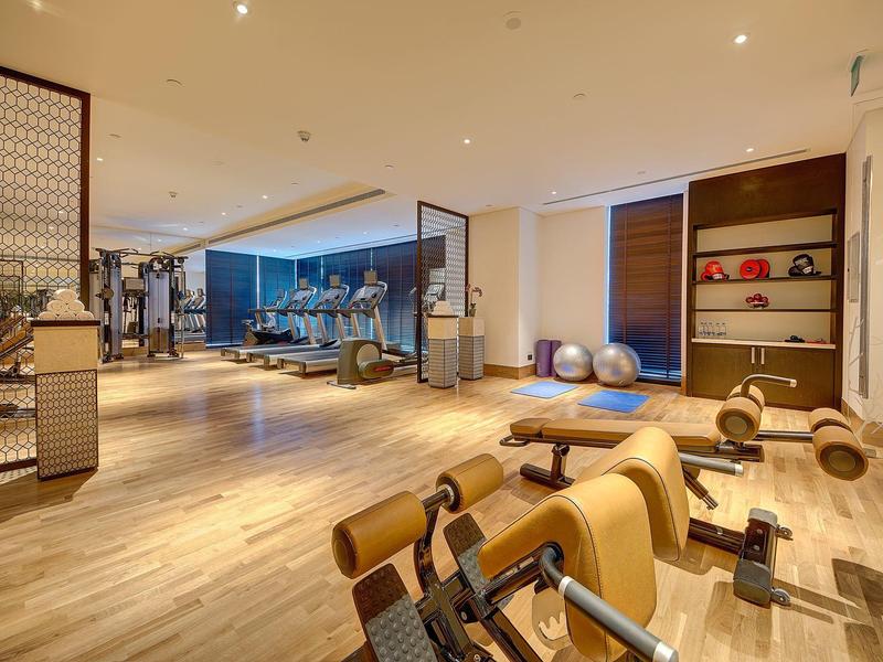 Ruime sportschool met houten vloer, diverse fitnessapparatuur en fitnessballen in een hotel