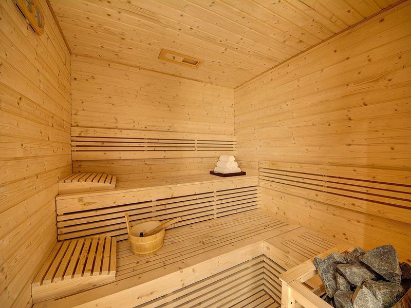 In houten panelen uitgevoerde sauna met banken, emmer, schep en verwarmde stenen.