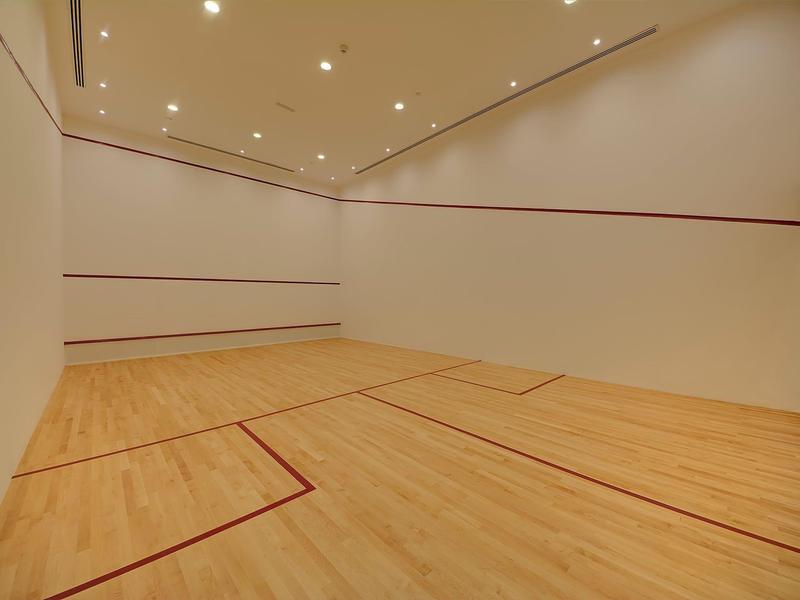 Indoor squashbaan met houten vloer en witte muren onder heldere plafondlampen