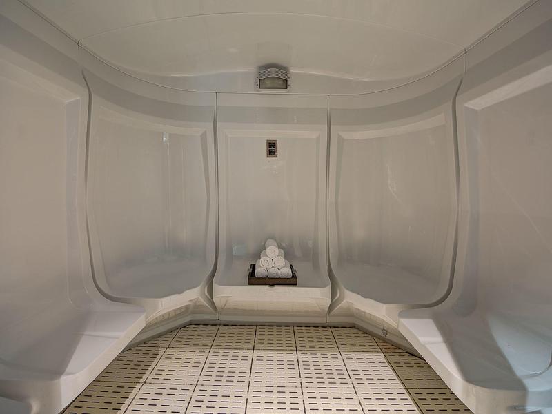 Lege witte saunaruimte met houten vloer en centrale kachel met stenen.