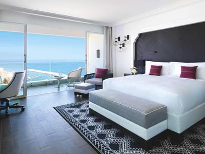 Modernes Hotelzimmer mit großem Bett, Panoramafenster und Meerblick.