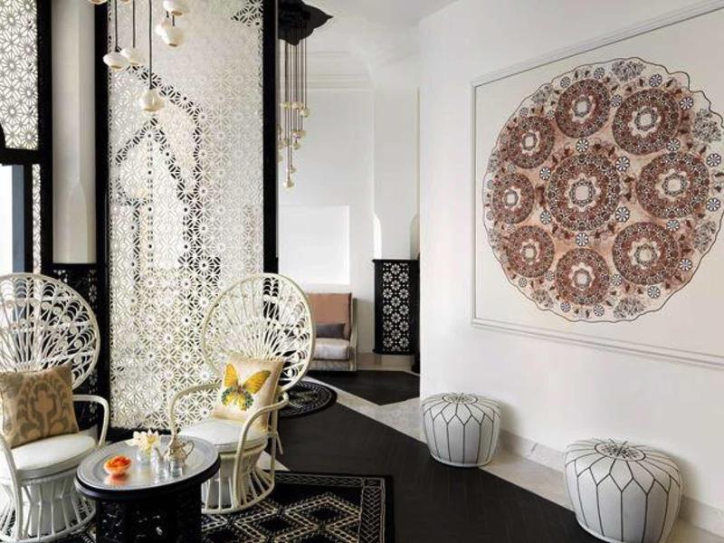 Modernes Wohnzimmer mit weißen Stühlen, schwarzem Boden und großem, runden Wandbild in Braun.