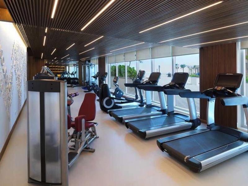 Moderne Fitnesseinrichtung mit Laufbändern, Trainingsgeräten und großer Glasfront.