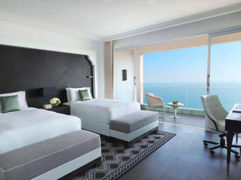 Modernes Hotelzimmer mit zwei Einzelbetten, großem Fenster und Meerblick.