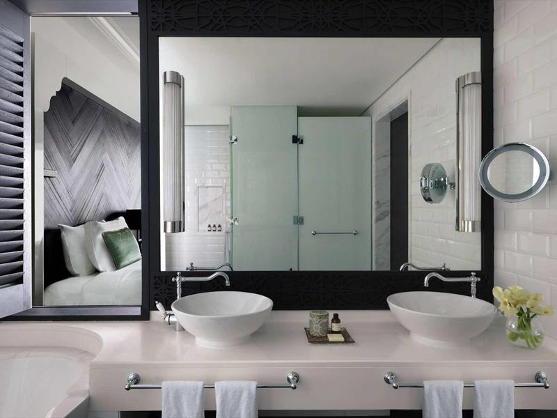 Modernes Badezimmer mit Doppelwaschbecken, großem Spiegel, Glasdusche und weißen Fliesen.