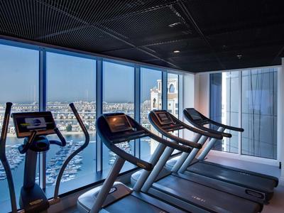 Moderní posilovací zařízení s výhledem na město v hotelové posilovně s velkými okny.