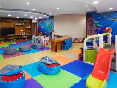 Bunter Spielraum mit weichen Matten, Sitzsäcken, Rutsche und Wandbildern von Meeresbewohnern.