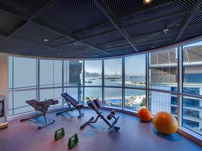 Moderní posilovna s výhledem na město a velkými okny.