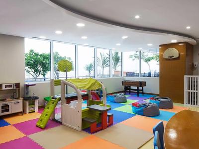 Bunter Spielbereich mit Rutsche, Kartonturm, Spielküche und großer Fensterfront im Hintergrund.