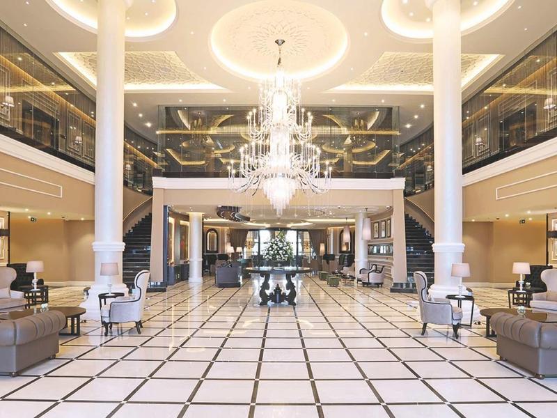 Große helle Lobby mit marmoriertem Boden, prächtigen Kronleuchtern und modernen Möbeln.