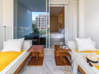 Zwei Sonnenliegen mit gelben Polstern auf einem Balkon mit Blick auf ein Wohngebäude.