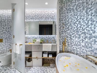 Modernes Badezimmer mit Mosaikwandfliesen, freistehender Badewanne und integriertem Waschbecken