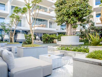 Moderner Außenbereich eines Hotels mit weißen Sitzmöglichkeiten und grünen Pflanzen.