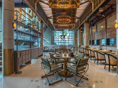 Eleganter Gastraum mit runden Tischen, Lederstühlen, Kronleuchtern und großem Fensterfront.