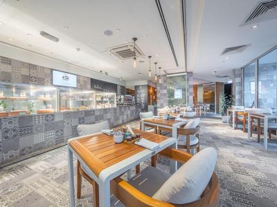 Nowoczesna, jasna restauracja z drewnianymi stołami i dużymi oknami z widokiem na miasto.