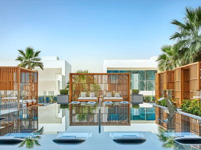 Moderner Poolbereich mit Liegen, Palmen und Holzverkleidungen bei klarem Himmel