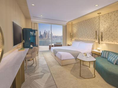 Modern eingerichtetes Hotelzimmer mit Blick auf eine Stadt und komfortabler Sitzgruppe.