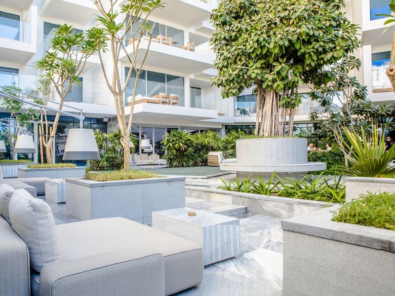 Moderner Außenbereich eines Hotels mit weißen Sitzmöglichkeiten und grünen Pflanzen.