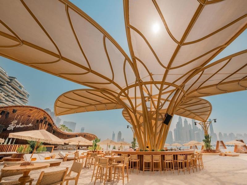 Outdoor-Barbereich mit überdachter, schirmförmiger Struktur und Stadtblick bei klarem Himmel