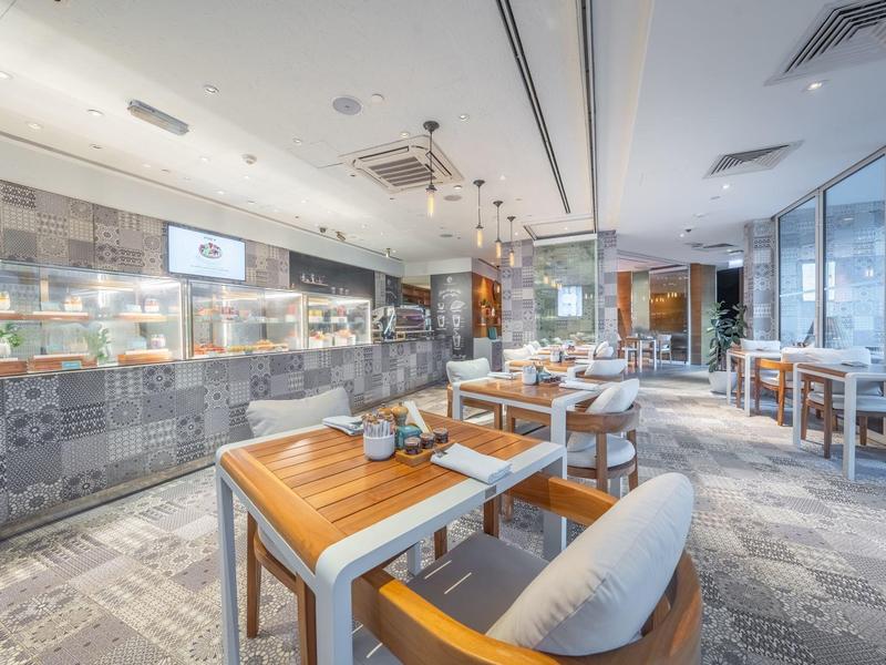 Modernes Restaurant mit Holztischen, gepolsterten Stühlen und großem Fenster mit Stadtblick.