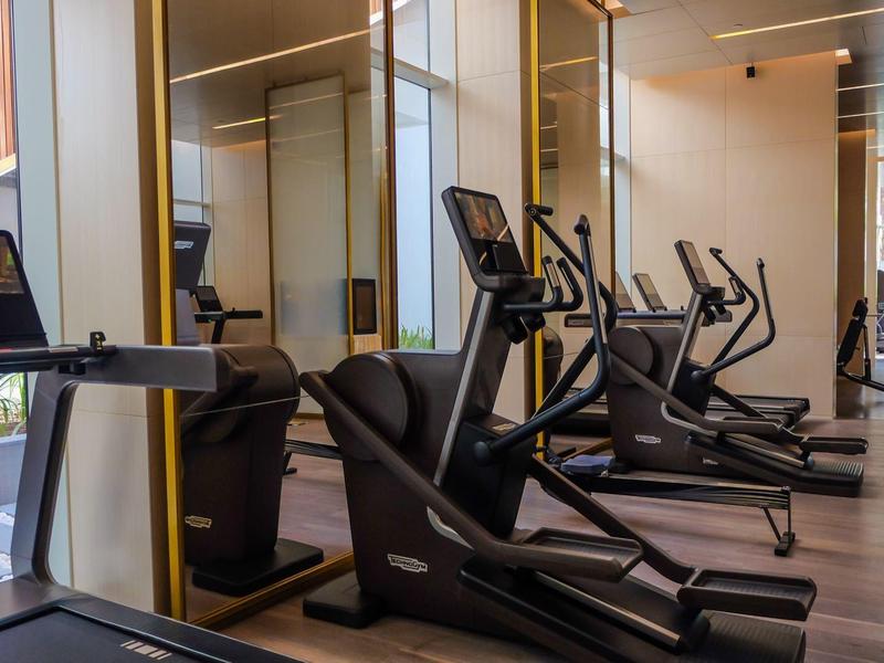 Moderner Fitnessraum mit elliptischen Trainern und großen Fenstern für natürliches Licht.