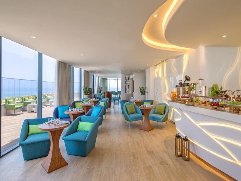 Helles, modernes Restaurant mit blauen Sesseln, großen Fenstern und Beleuchtung an der Decke.