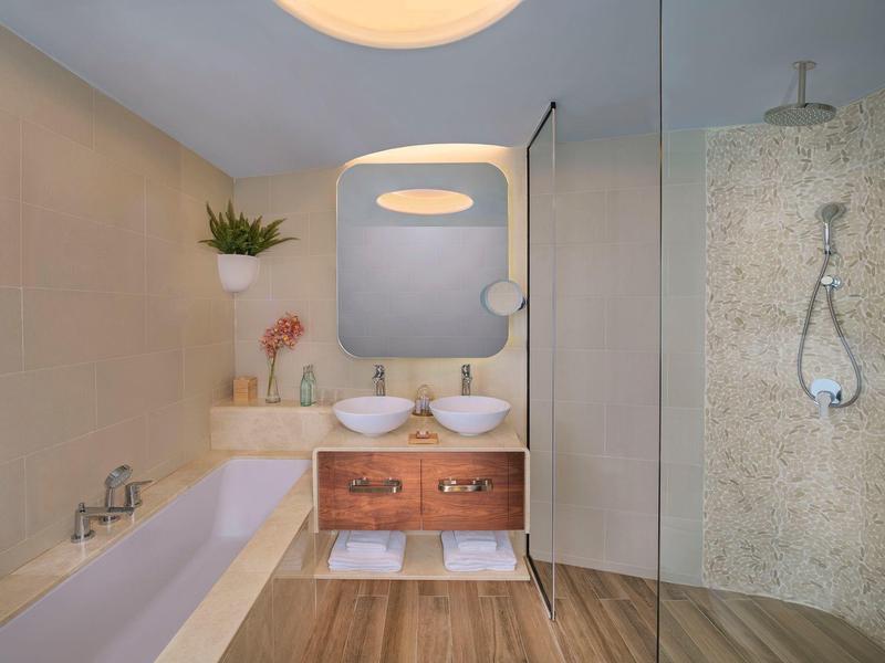 Modernes Badezimmer mit Badewanne, Doppelwaschbecken, Holzschrank und begehbarer Glasdusche.