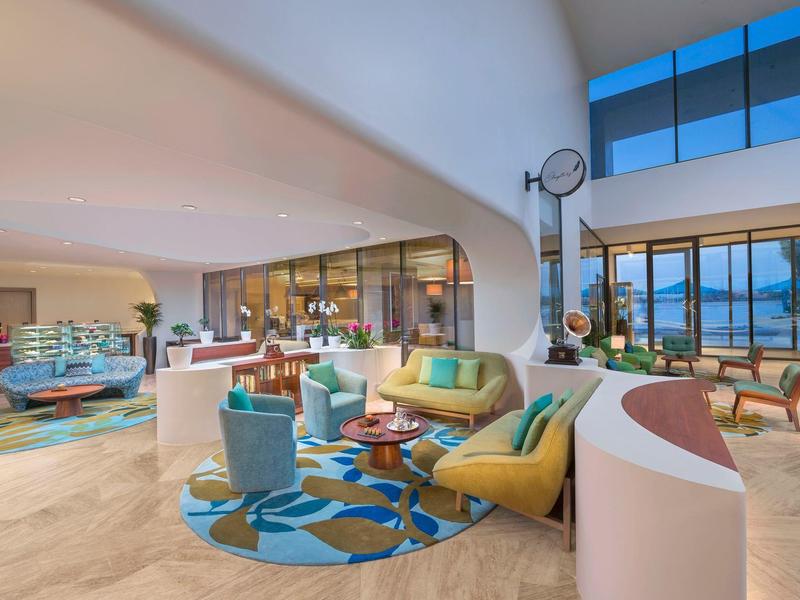 Großzügiges Wohnzimmer mit bunten Möbeln, großen Fenstern und modernem, offenem Design.