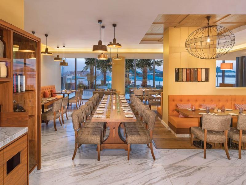 Moderner, heller Gastraum mit Holzmöbeln, großen Fenstern und weißem Marmorfußboden.